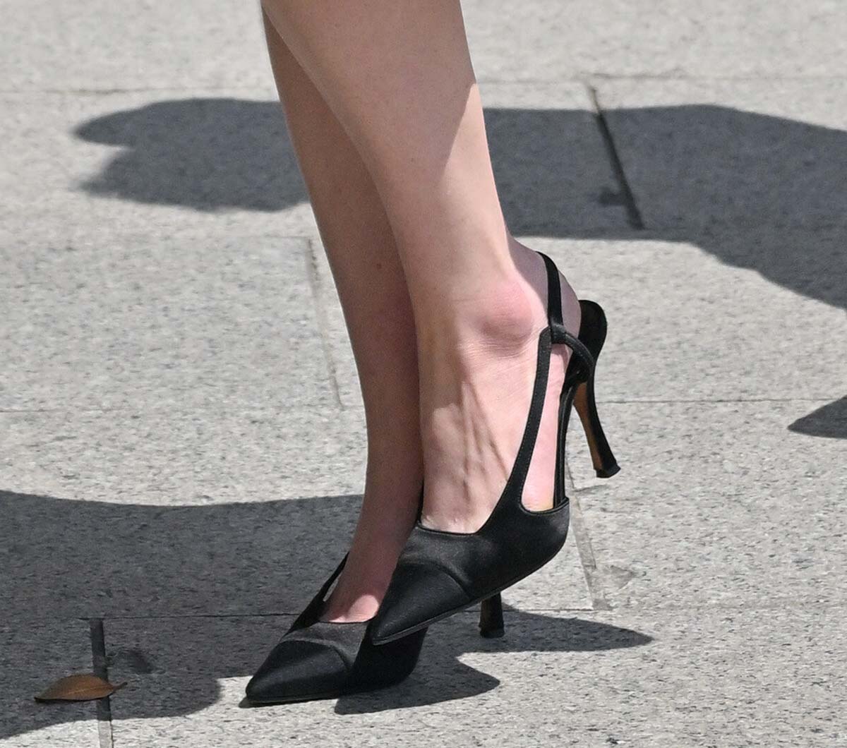 Sadie Sink completes her elegant black-and-white look with black satin pointed-toe slingback pumps by Chanel