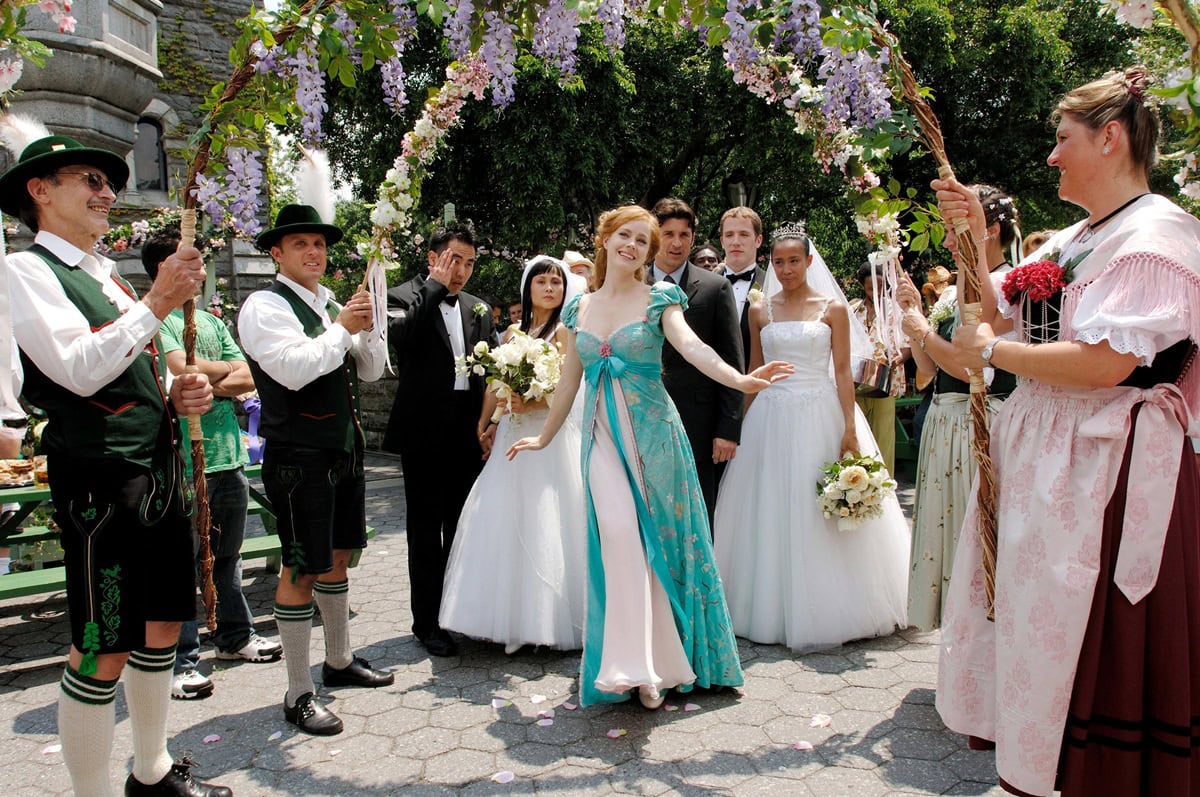 Amy Adams enchants in Giselle’s teal floral robe dress with puffed sleeves and a flowing pink underlayer, paired with soft ivory heels that highlight her fairytale elegance during the whimsical Central Park wedding scene in Enchanted
