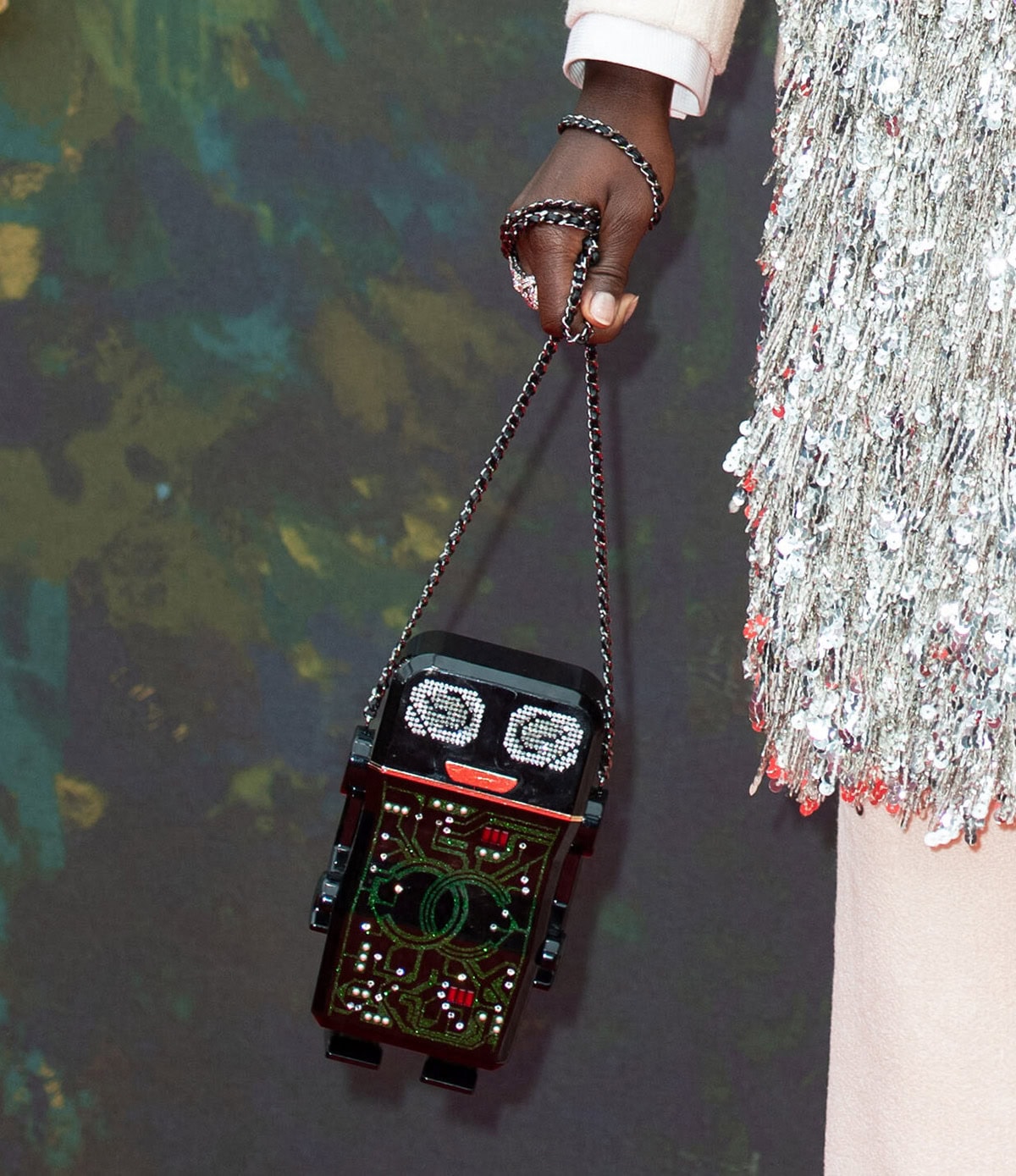 Lupita Nyong'o adds her signature whimsical touch to the holiday outfit with a robot-shaped bag from Chanel's 2017 collection