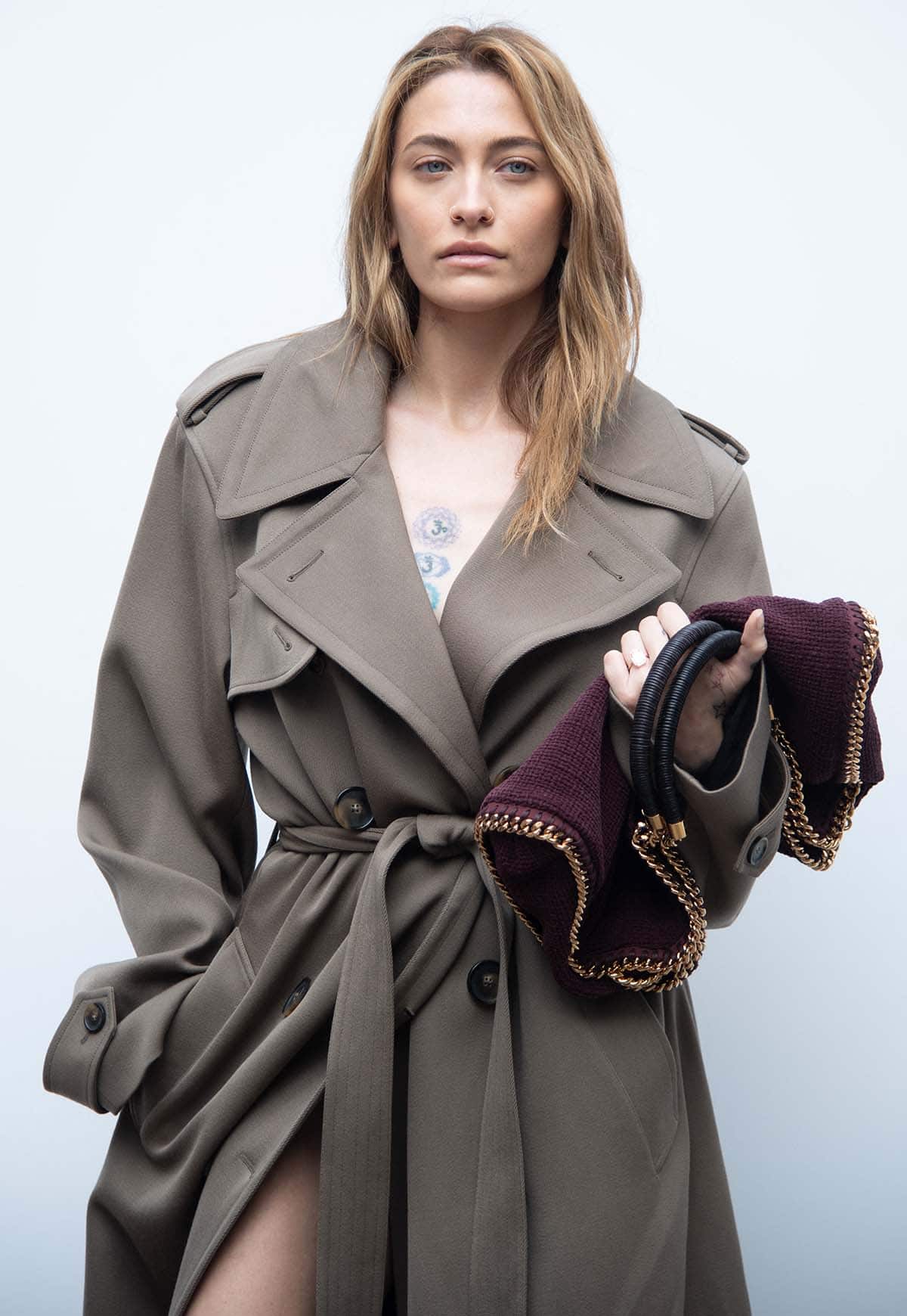Paris Jackson teams her coat dress with a burgundy interwoven Stella McCarney bag with gold chain trims and enhances the look's sultriness with a tousled hairstyle and nude makeup