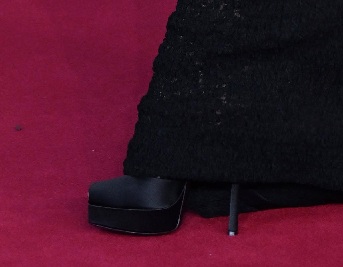 Zoe Saldaña opts for the Saint Laurent La Scandale platform pumps in shiny black satin, adding edge and elegance to the look