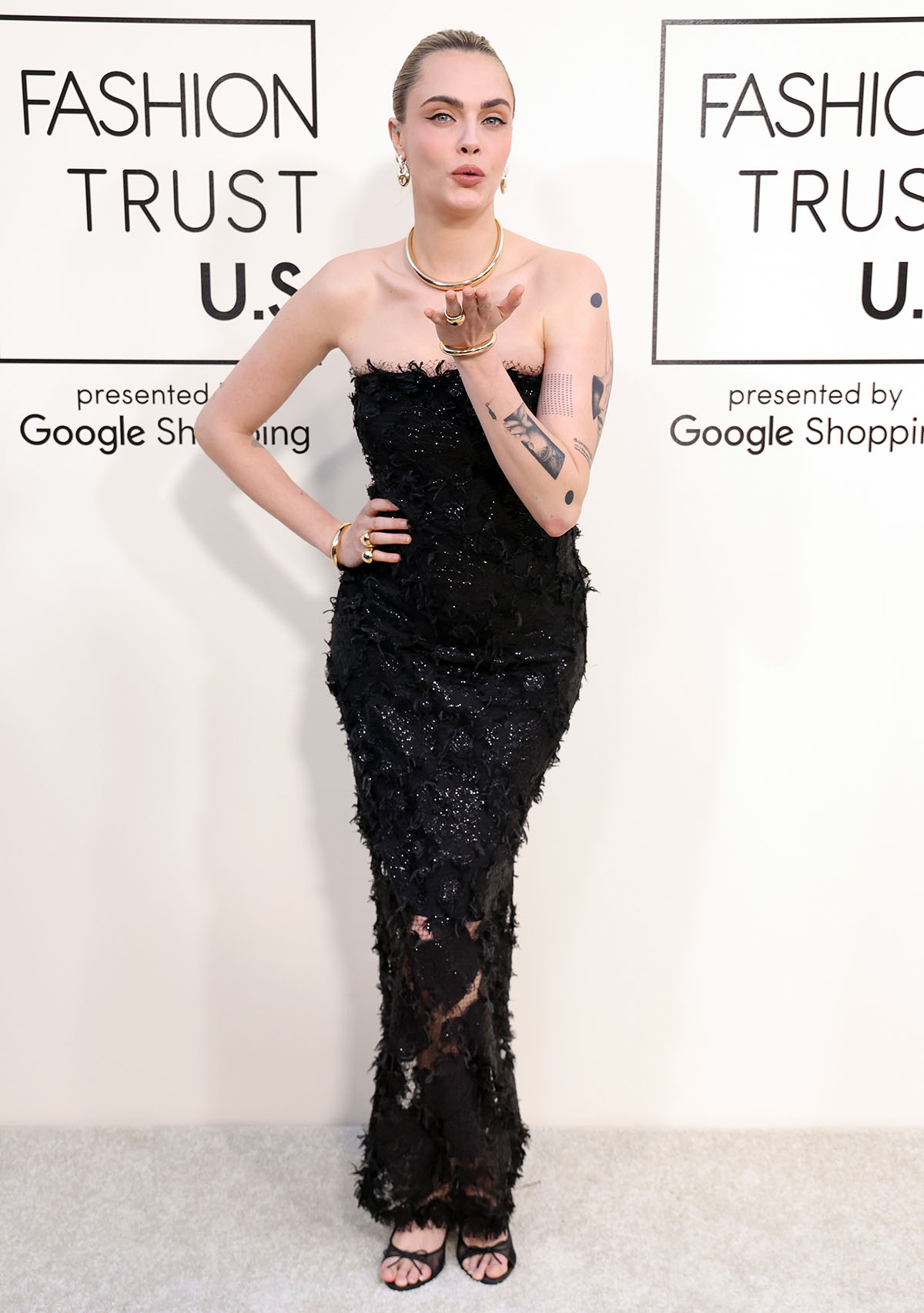 Cara Delevingne teams her see-through pumps with a black Cult Gaia dress covered in feathers and sparkling beads