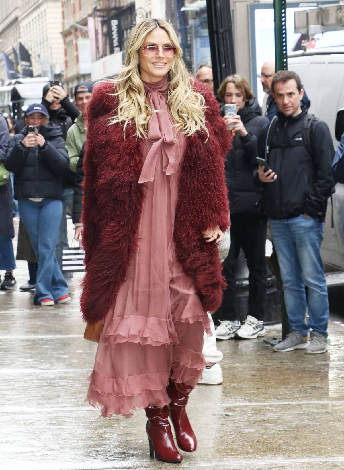 Heidi Klum looks feminine and gorgeous in a flowy pink chiffon dress with subtle pleating, tiered ruffles, and a high neck with a pussy bow
