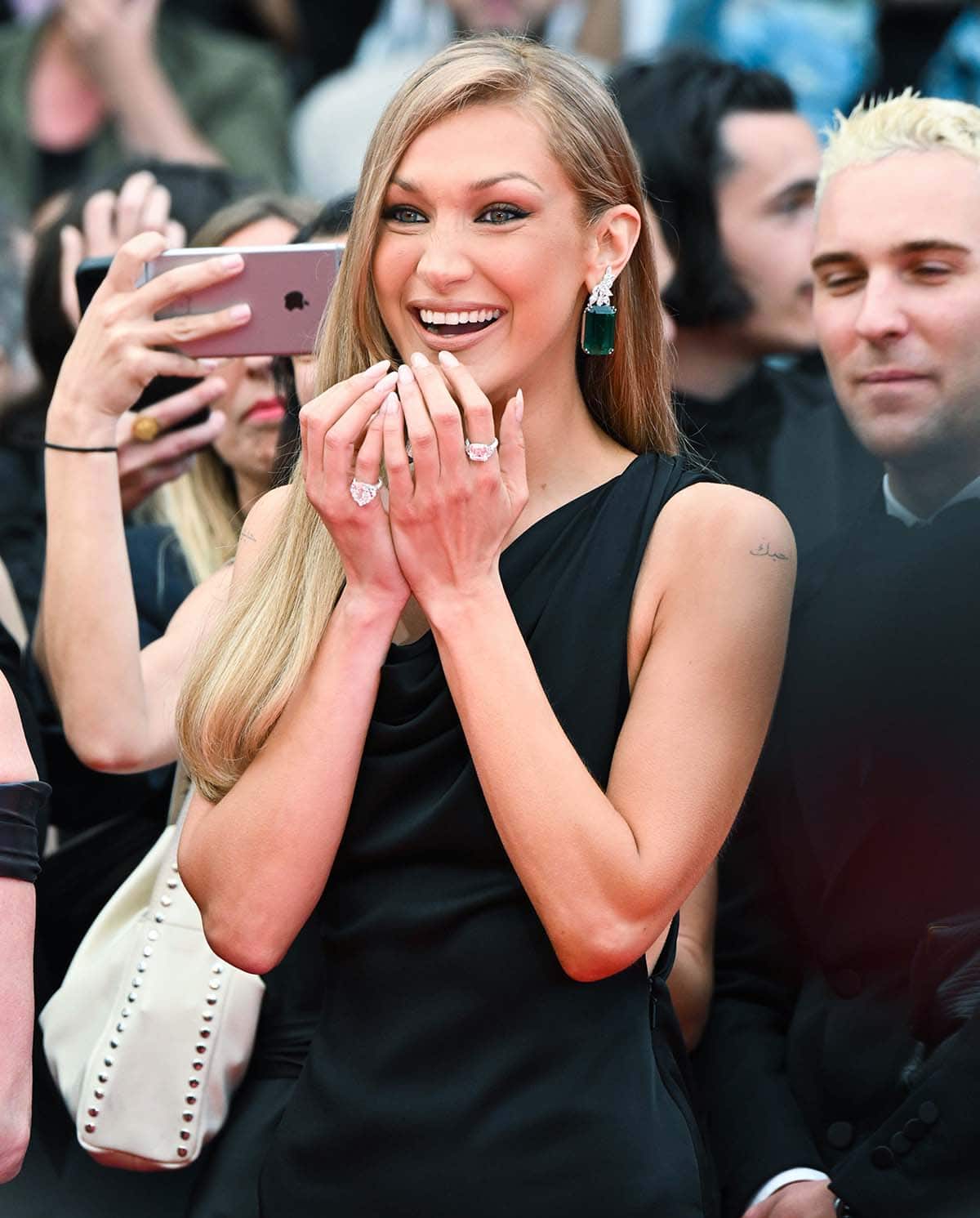 Bella Hadid debuts her newly dyed honey-blonde hair on the Cannes Film Festival red carpet and styles her look with emerald and diamond jewelry by Chopard