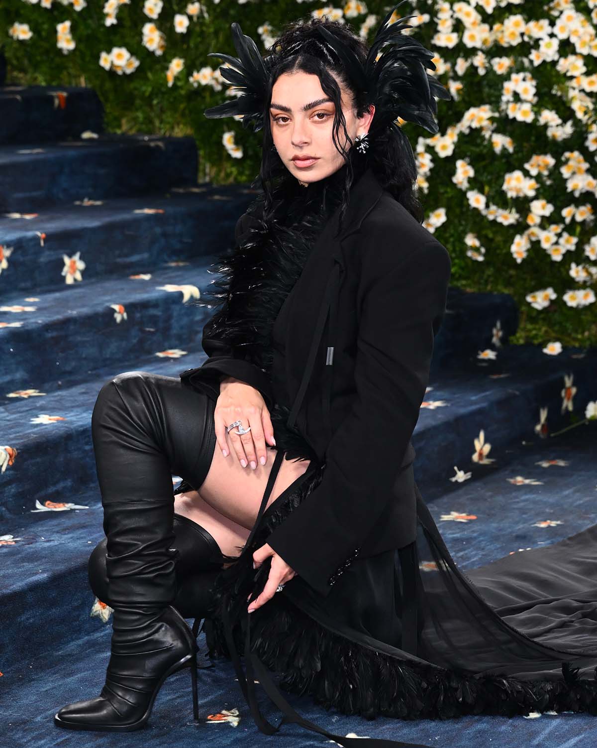 Charli XCX reimagines a three-piece tailored set with a cropped feather top, a cropped blazer, and a sheer maxi skirt with feather trims