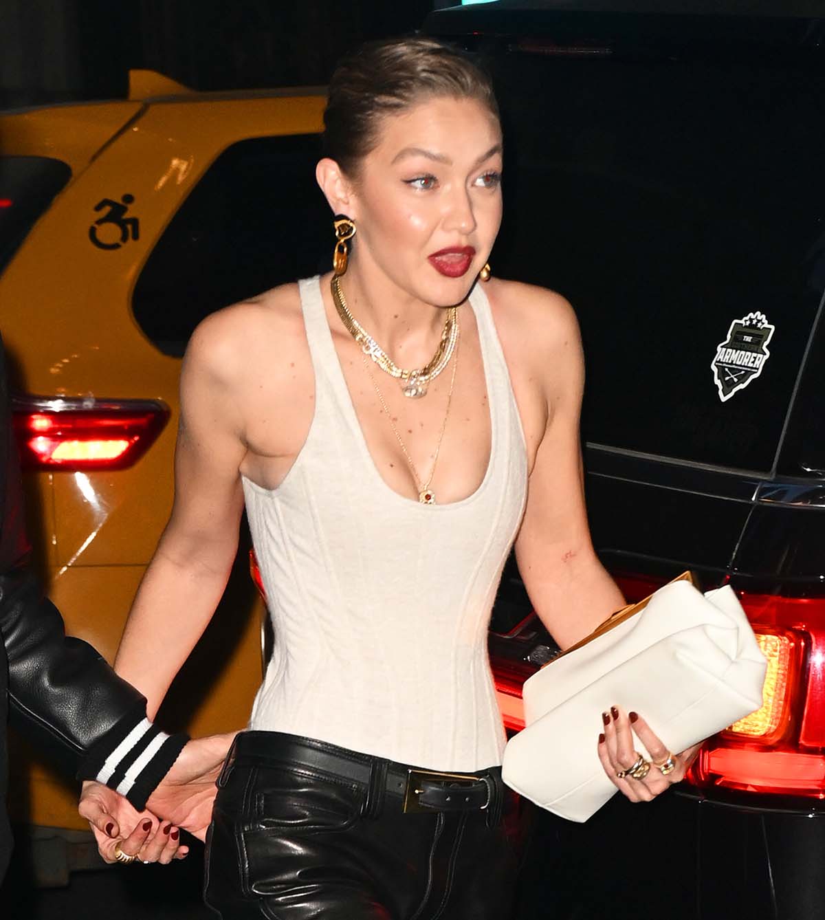 Gigi Hadid accessorizes her black and white ensemble with gold jewelry by Schiaparelli, Mystery Joy, Jacquie Aiche, and Anita Ko