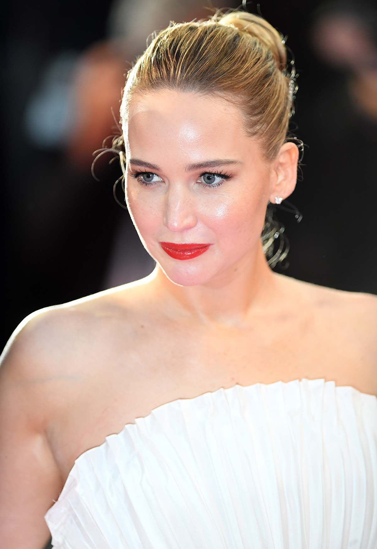 Jennifer Lawrence channels Old Hollywood glamour with mascara, red lipstick, and a clean bun hairstyle