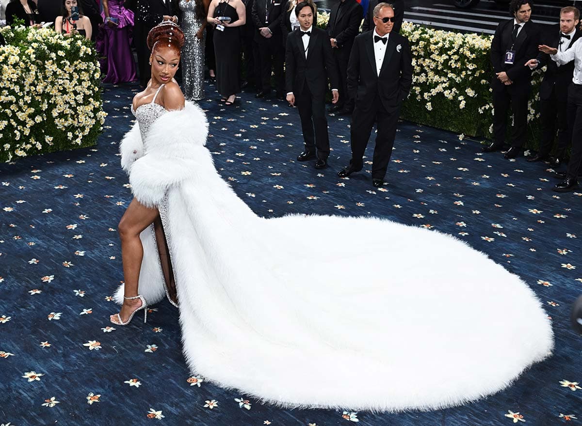 Megan Thee Stallion channels entertainer Josephine Baker in a silver sequin dress with a white fur coat and red three-tiered knotted ponytail