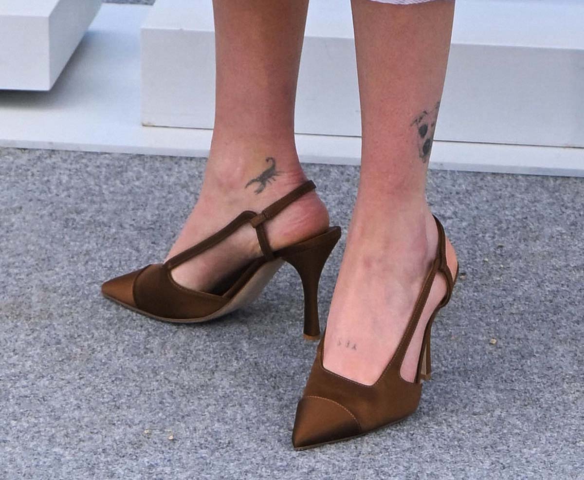 Zoey Deutch finishes her beige ensemble with custom brown satin slingback pumps, subtly revealing her ankle and foot tattoos for a chic-meets-edgy red carpet moment