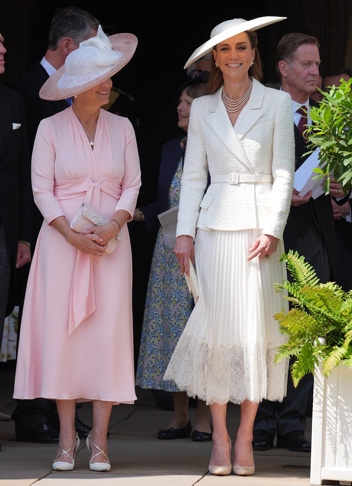 Kate Middleton, pictured with The Duchess of Edinburgh, is the epitome of summer elegance in a white Self-Portrait dress featuring a boucle tweed jacket bodice and a pleated midi skirt with a lace hem