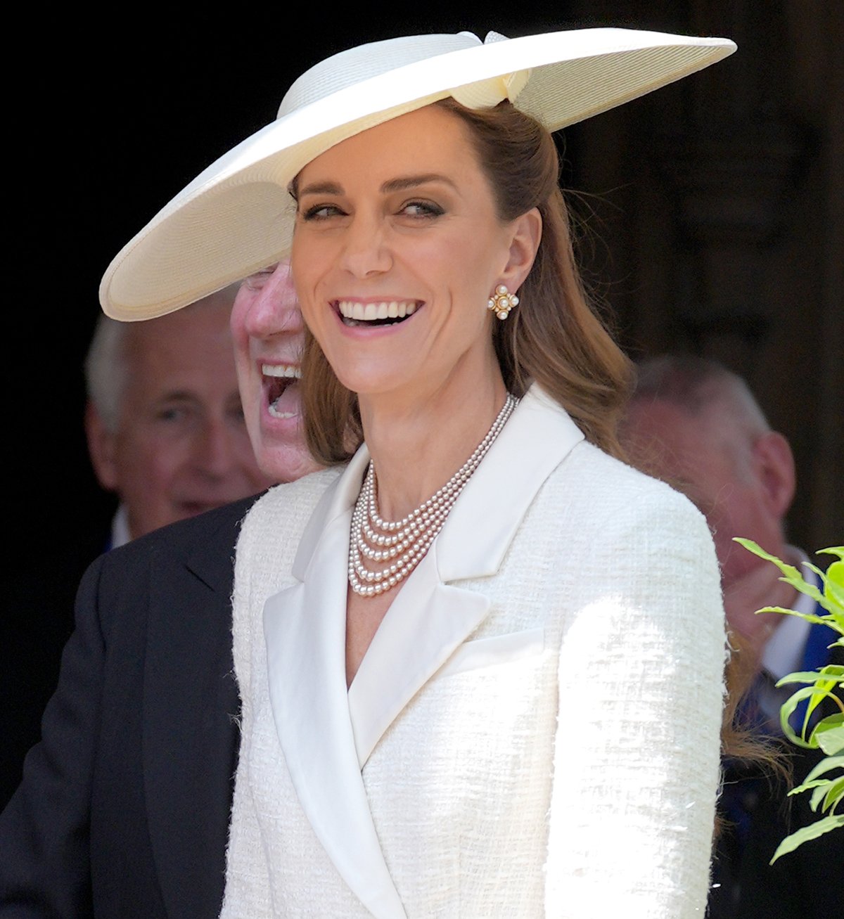 Kate Middleton styles her all-white summer look with a Susan Caplan 5-strand pearl necklace, pearl cluster earrings, and a wide-brimmed Sean Barrett hat