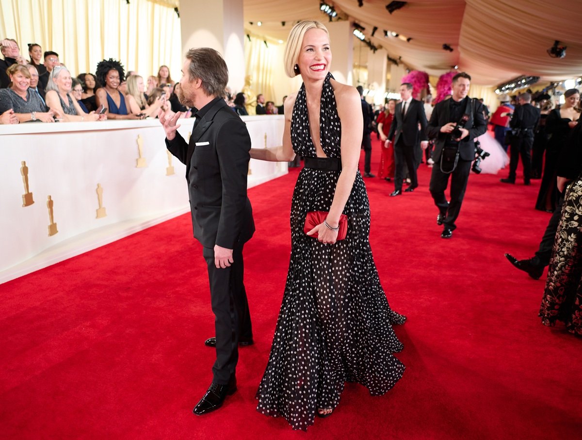 Leslie Bibb stuns in a plunging black-and-white polka-dot Dolce & Gabbana gown alongside Sam Rockwell in a sharp Dolce & Gabbana tuxedo on the 96th Oscars red carpet
