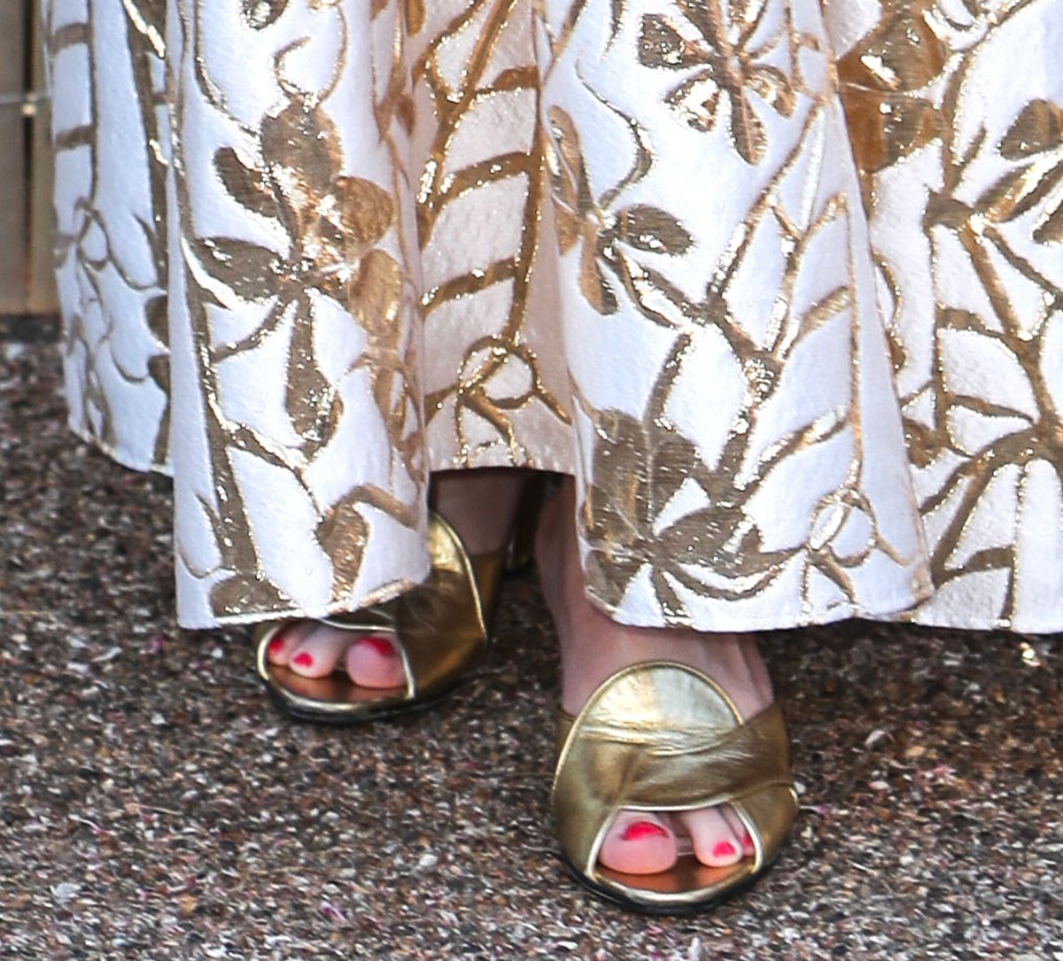 Rebel Wilson showcases her red pedicure in retro-style gold Gucci mules with crisscrossing straps and high heels