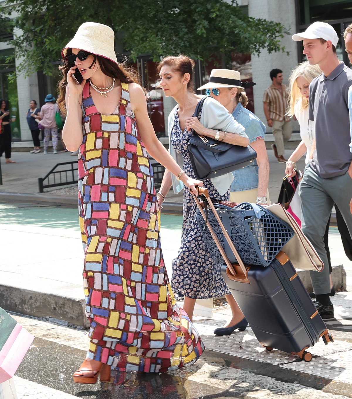 Anne Hathaway looks vacation-ready in a Gabriela Hearst Niki dress featuring colorful rectangular patchworks and a Shebobo crochet bucket straw hat