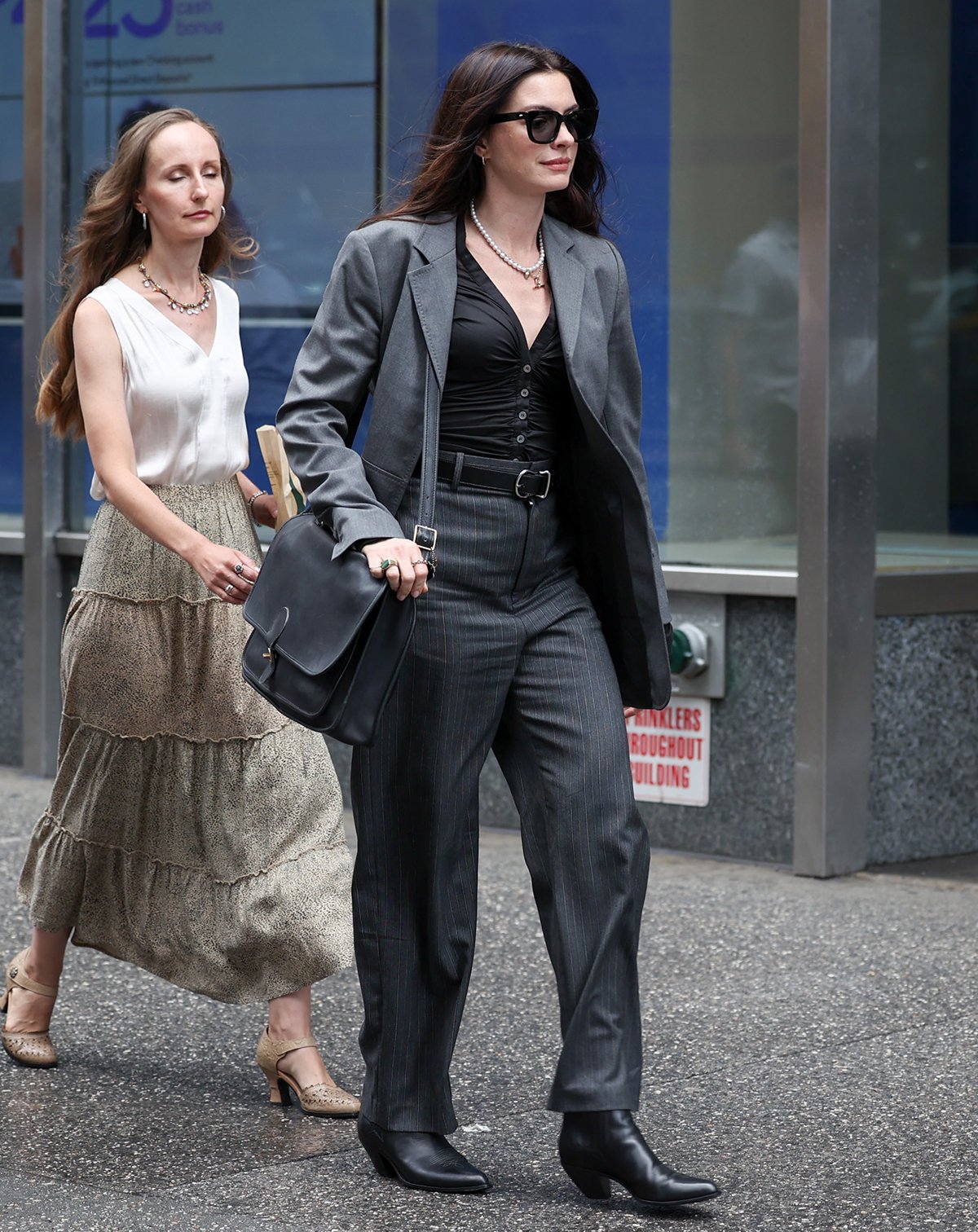 Anne Hathaway embraces serious girl-boss energy in an oversized gray blazer, pinstripe pants, and a black ruched blouse
