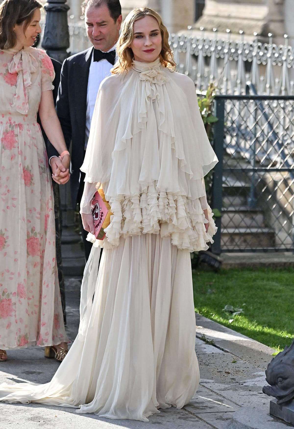 Diane Kruger graces the 2025 Bal d’Été in an airy ivory chiffon Alberta Ferretti gown with a soft bow tied at the high neck, cape sleeves, and layers of chiffon ruffles