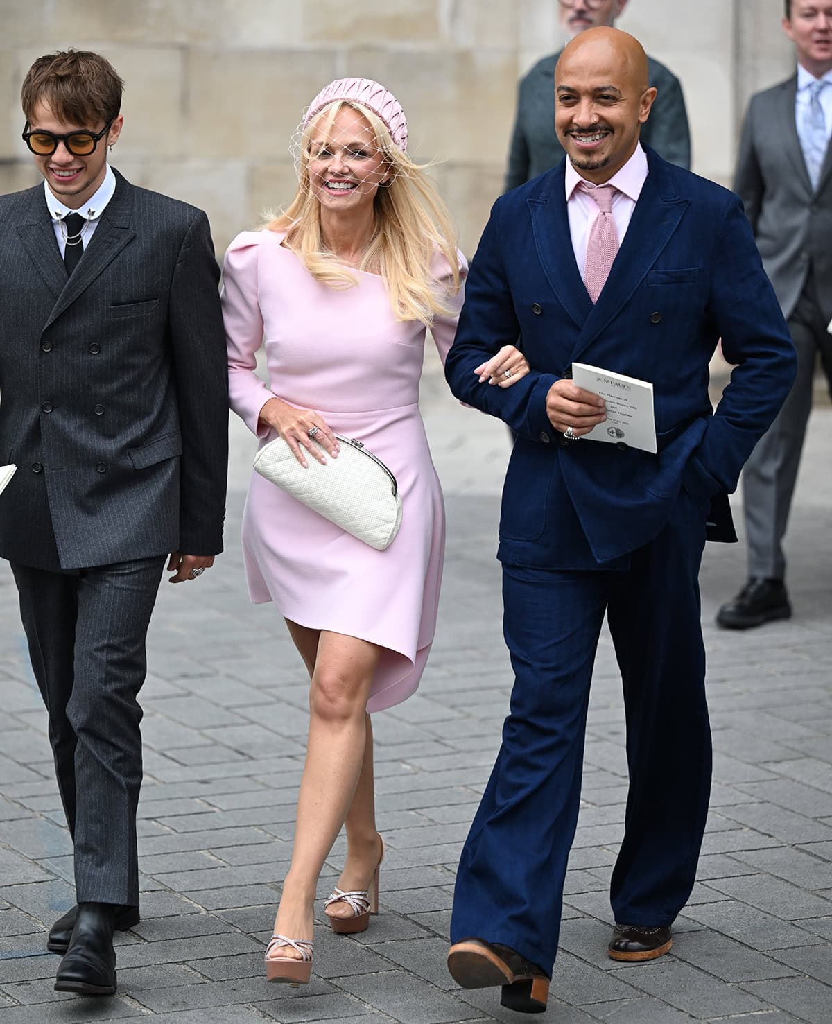 Emma Bunton channels her inner Baby Spice in a pink Roland Mouret asymmetrical minidress, a matching fascinator, and crystal-encrusted platform sandals