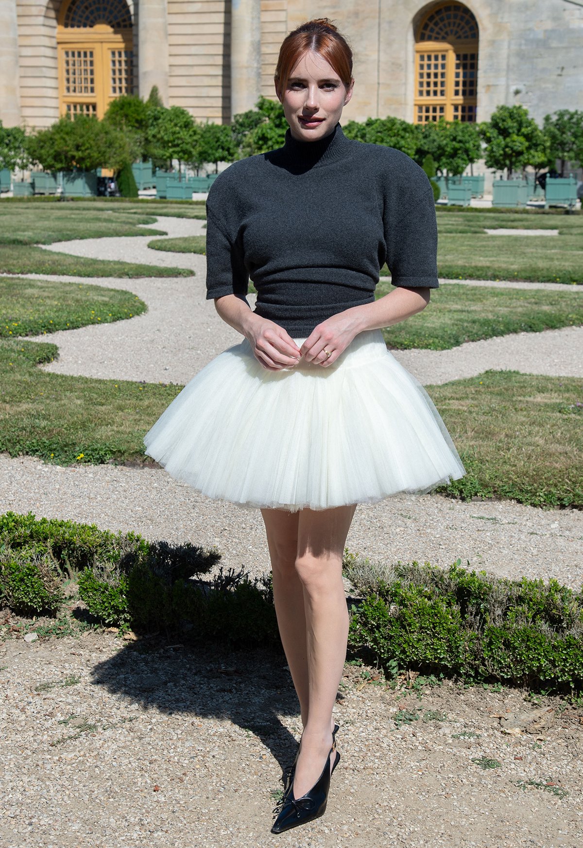 Emma Roberts parades her slim legs in a white tutu tulle skirt and a gray knit short-sleeved sweater with padded shoulders and a turtleneck by Jacquemus