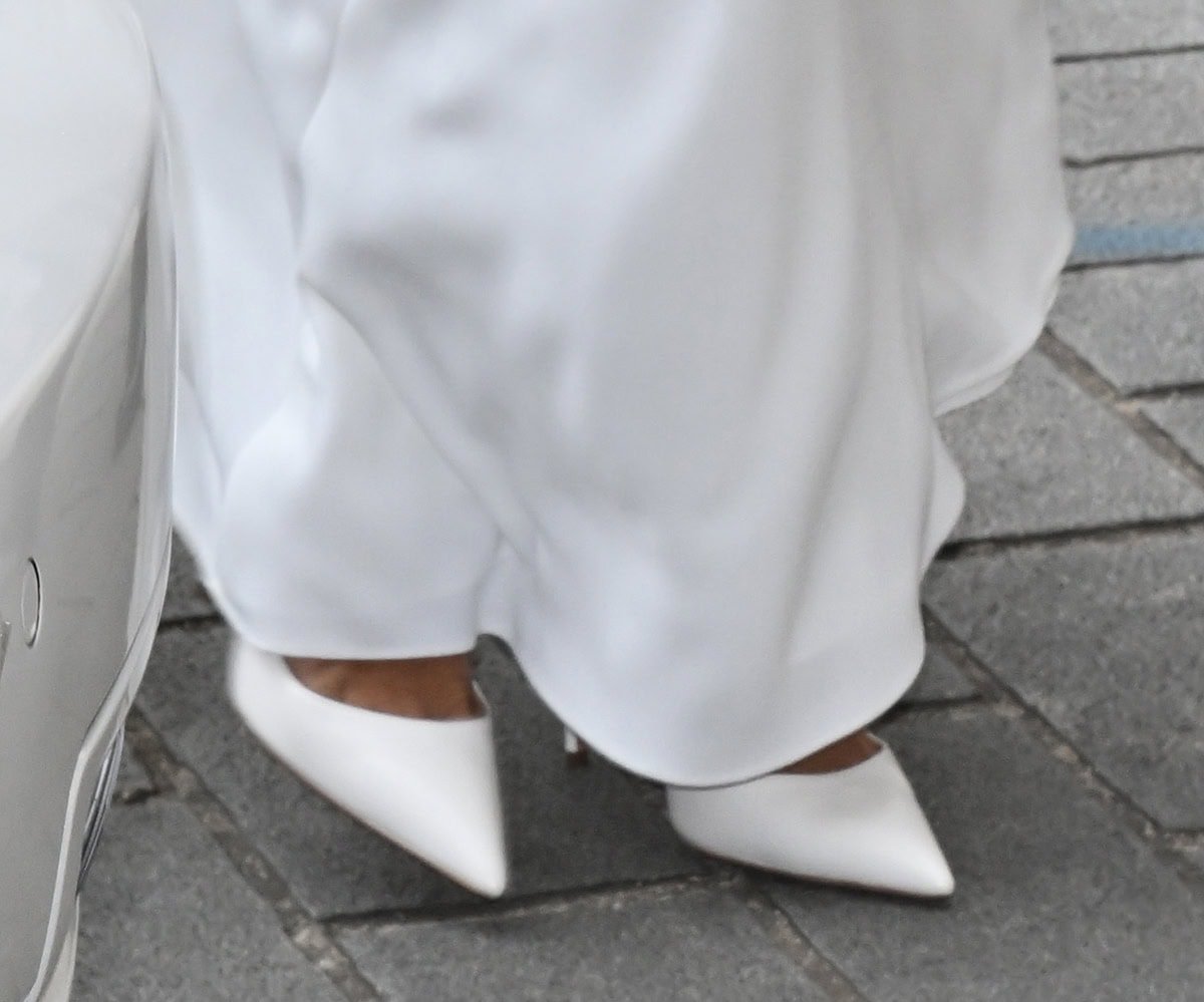 Mel B wears classic white wedding shoes with a sleek, contemporary, sharp silhouette, pointed toes, and stiletto heels