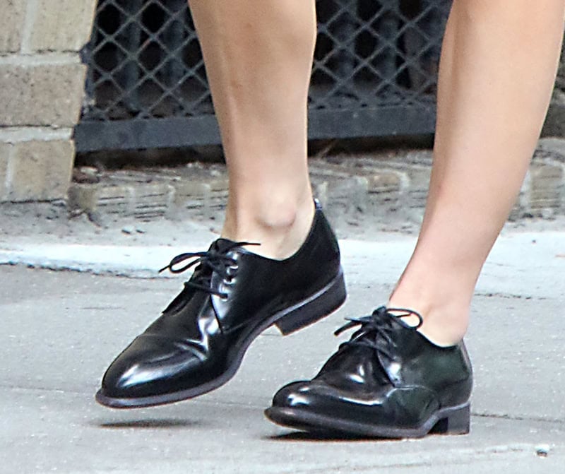 Natalie Portman teams her casual shorts with black leather Oxford shoes, enhancing the outfit’s sleek, androgynous edge