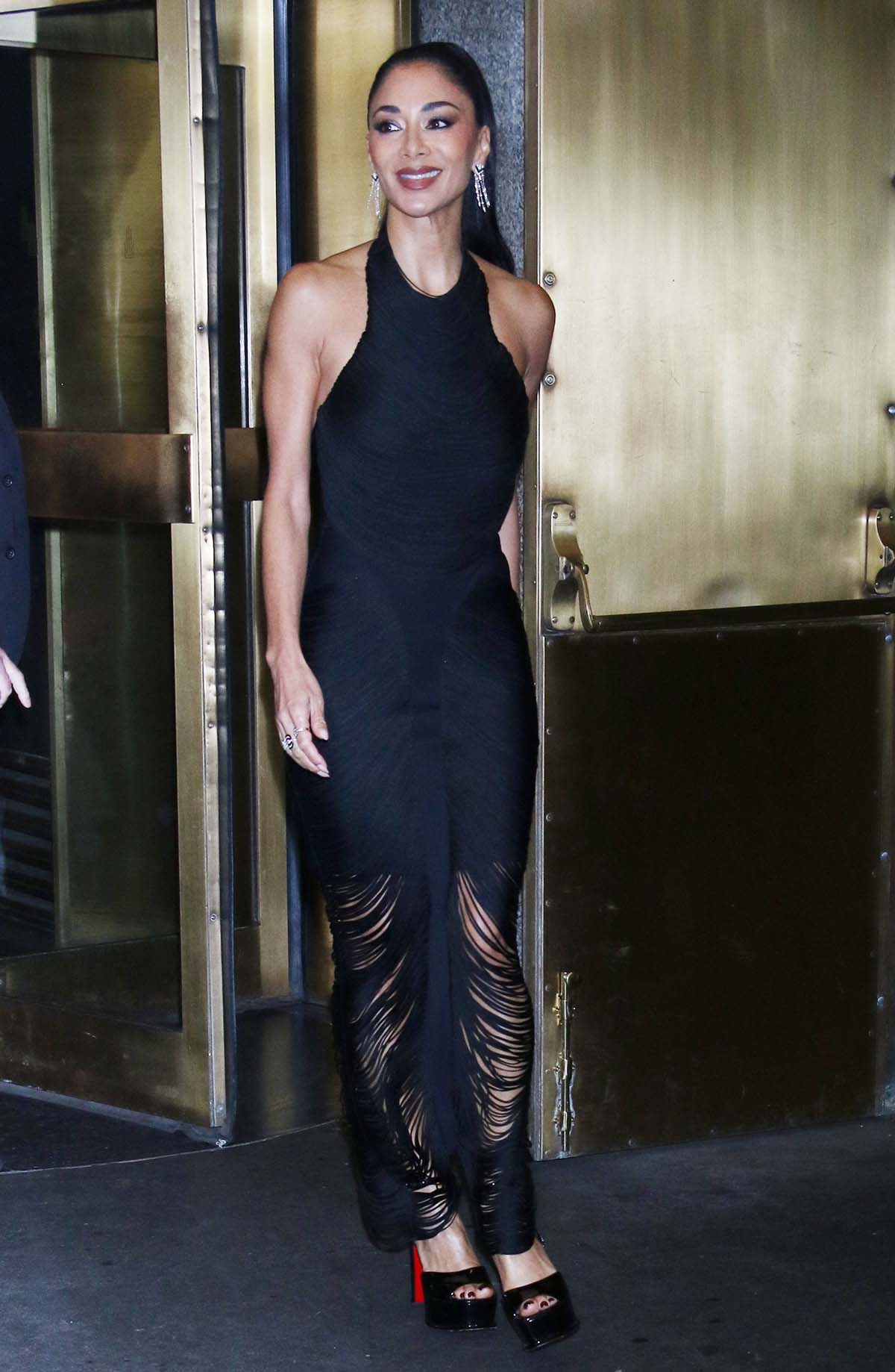 Nicole Scherzinger showcases her toned figure in a sultry yet glamorous LBD by Herve Leger, featuring shredded slashes cascading from the halter neckline to the ankle-length hem