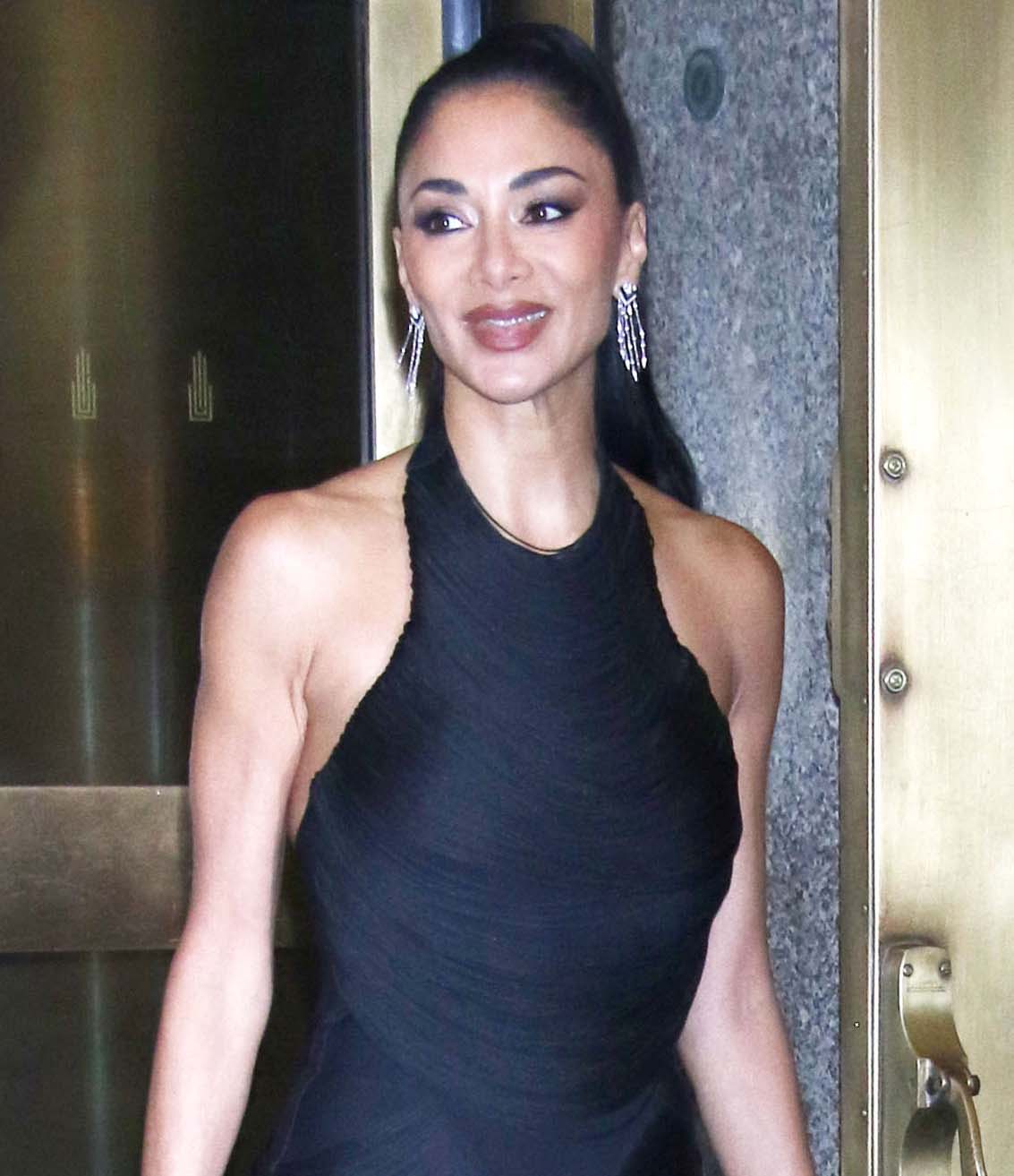 Nicole Scherzinger opts for a sultry beauty look, styling her long raven tresses in a high ponytail and highlighting her features with smokey eyeshadow, heavy eyeliner, warm blush, and mocha lip color