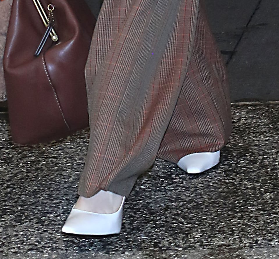 Rachel Brosnahan teams her brown plaid ensemble with sleek white leather pumps by Jude