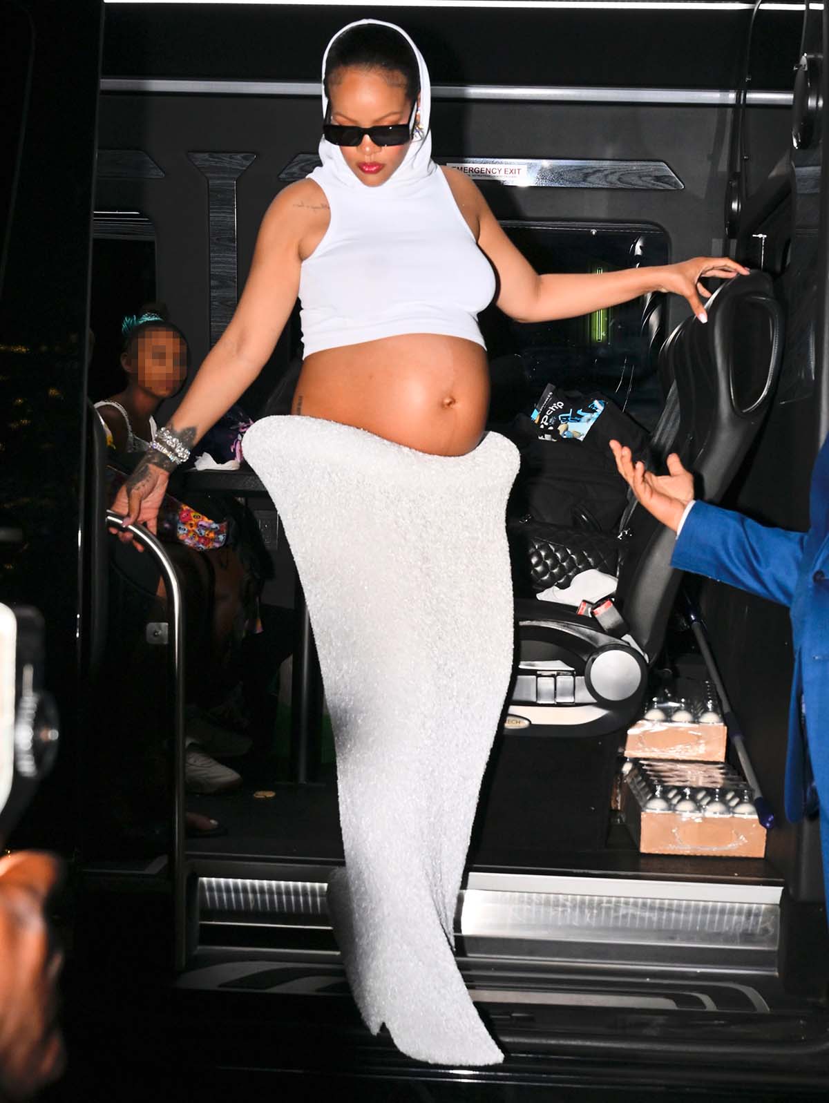 Rihanna shows off her baby bump in a white Alaïa hooded crop top with a low-rise tapered maxi skirt featuring an architectural waist