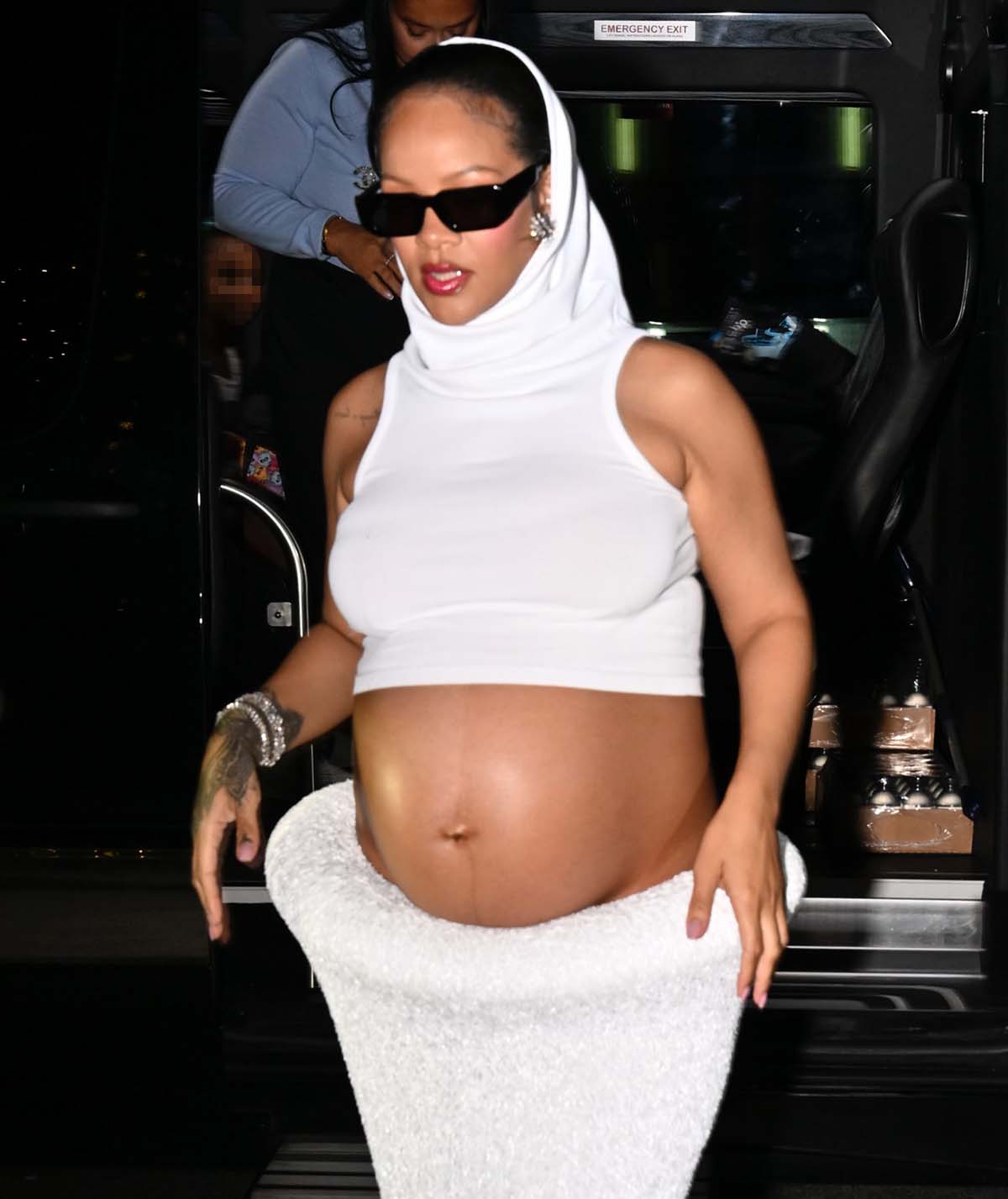 Rihanna accessorizes her futuristic ensemble with sleek black sunglasses and diamond jewelry and highlights her features with rosy blush and red lipstick
