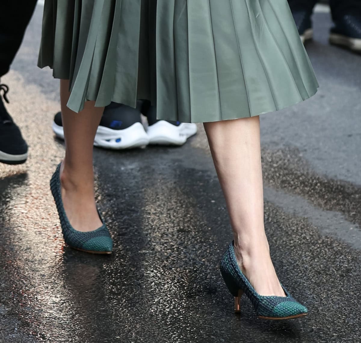 Anne Hathaway teams her white shirt and green pleated midi skirt with navy and green woven pumps with kitten heels by Gabriela Hearst