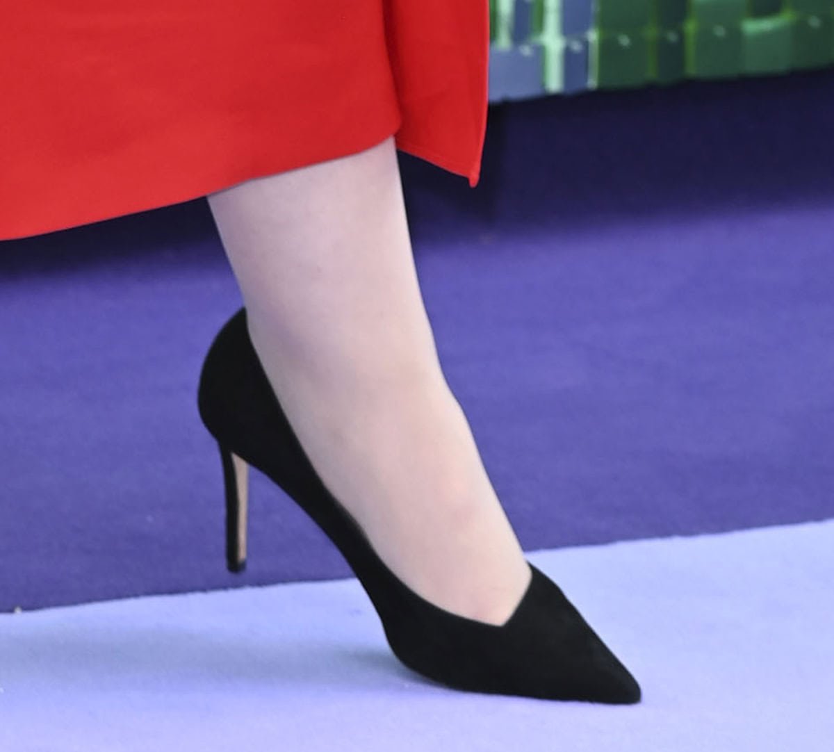 Jamie Lee Curtis teams her red cape midi dress with classic black suede pointy pumps with asymmetrical vamps