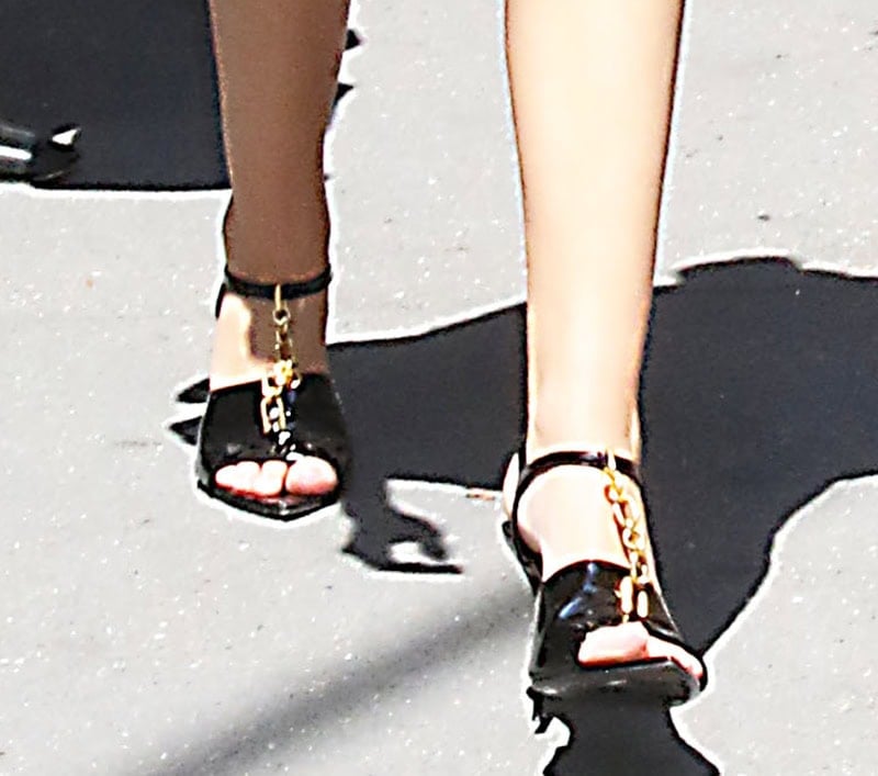 Julia Butters completes her playful yet sophisticated monochromatic ensemble with Balmain Sync sandals featuring a gold-tone chain T-strap, open toes, ankle straps, and high heels