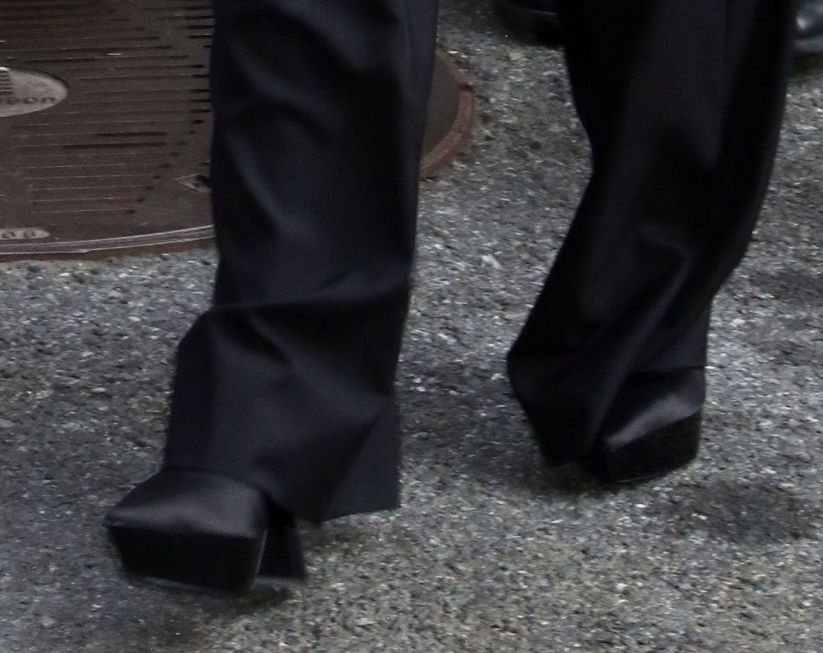 Julia Garner completes her chic, tailored look with black satin pumps with pointed toes and thick platforms