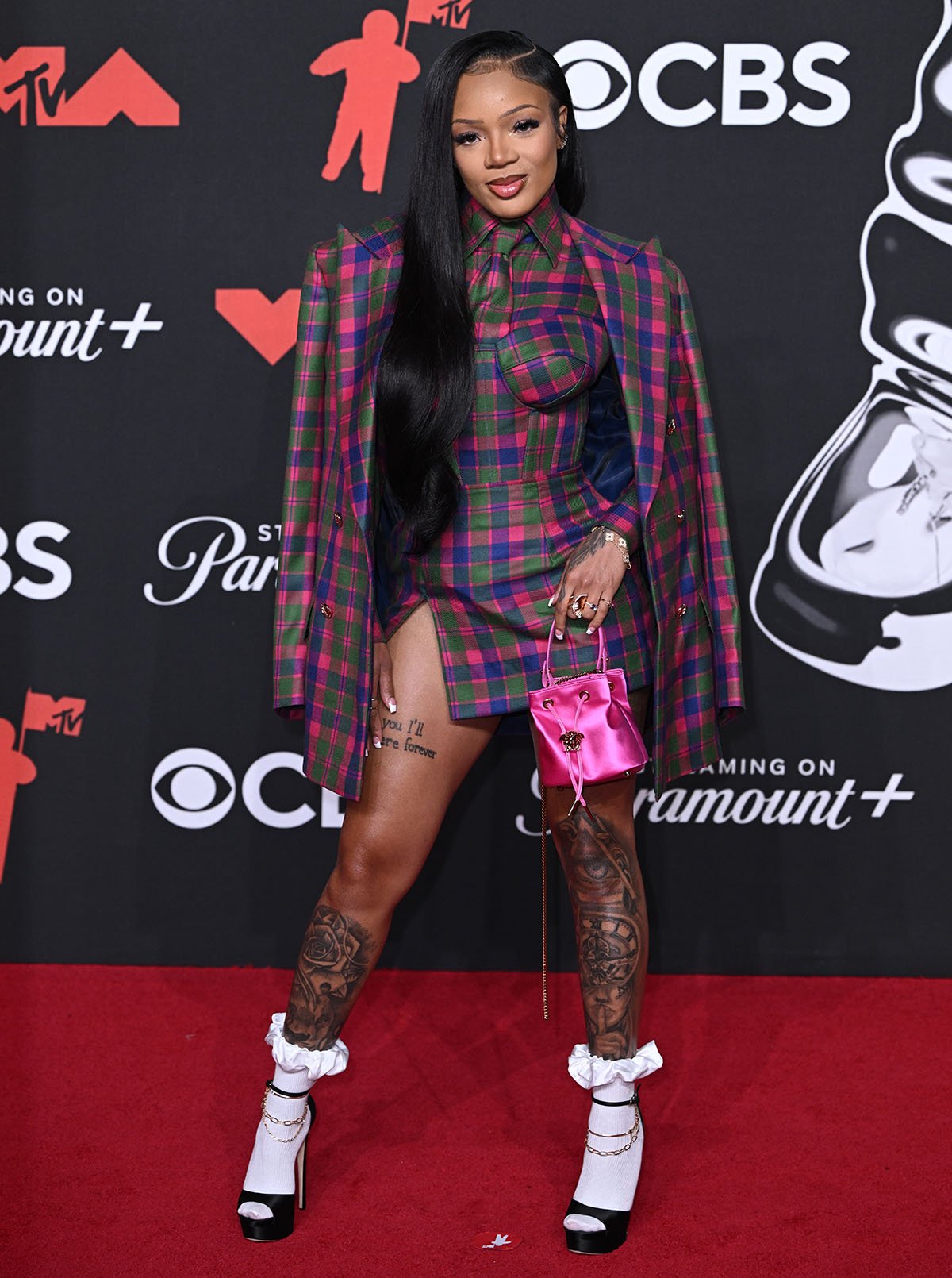GloRilla teams her schoolgirl black-shoes-and-white-socks combination with a multicolored plaid skirt suit by Helen Anthony