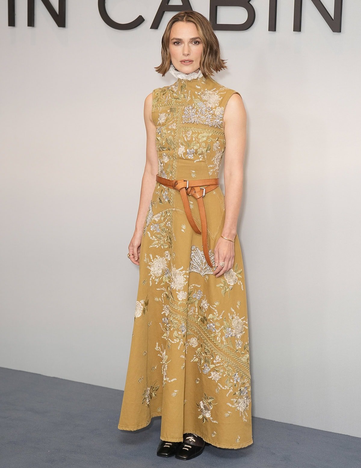 Keira Knightley looks stunning in a mustard-yellow sleeveless dress by Erdem featuring floral and crystal embroideries and a white ruffled high collar