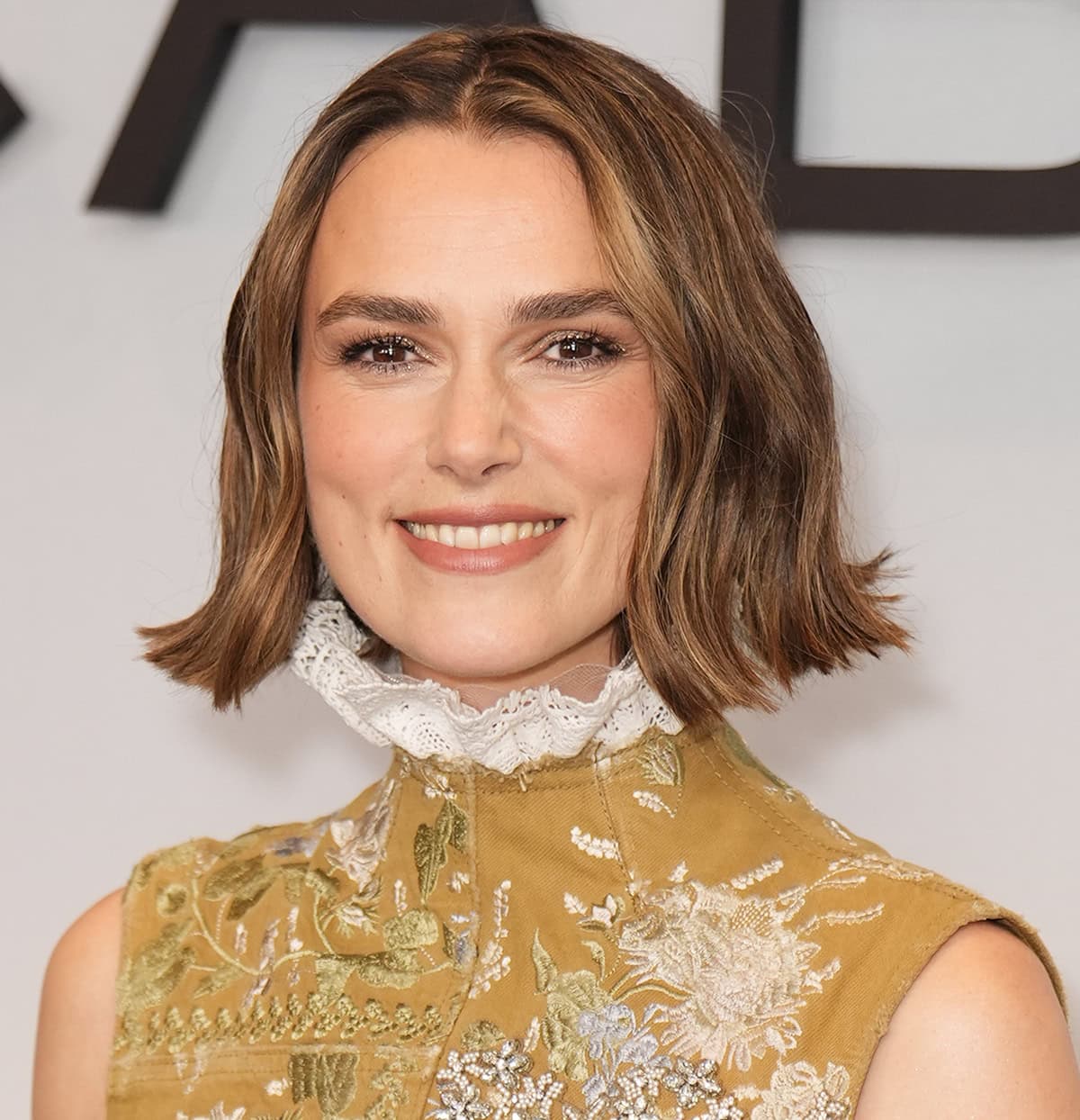 Keira Knightley wears her signature French bob and highlights her features with glittering eyeshadow and soft neutral makeup