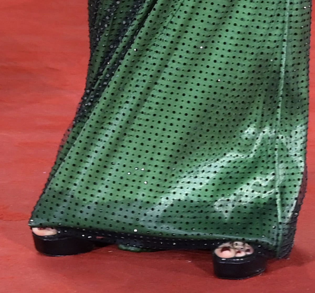 Laura Dern completes her emerald green Armani Privé gown with black open-toe platform heels, the bold lift of the shoes subtly peeking out beneath the gown’s crystal-embroidered hem