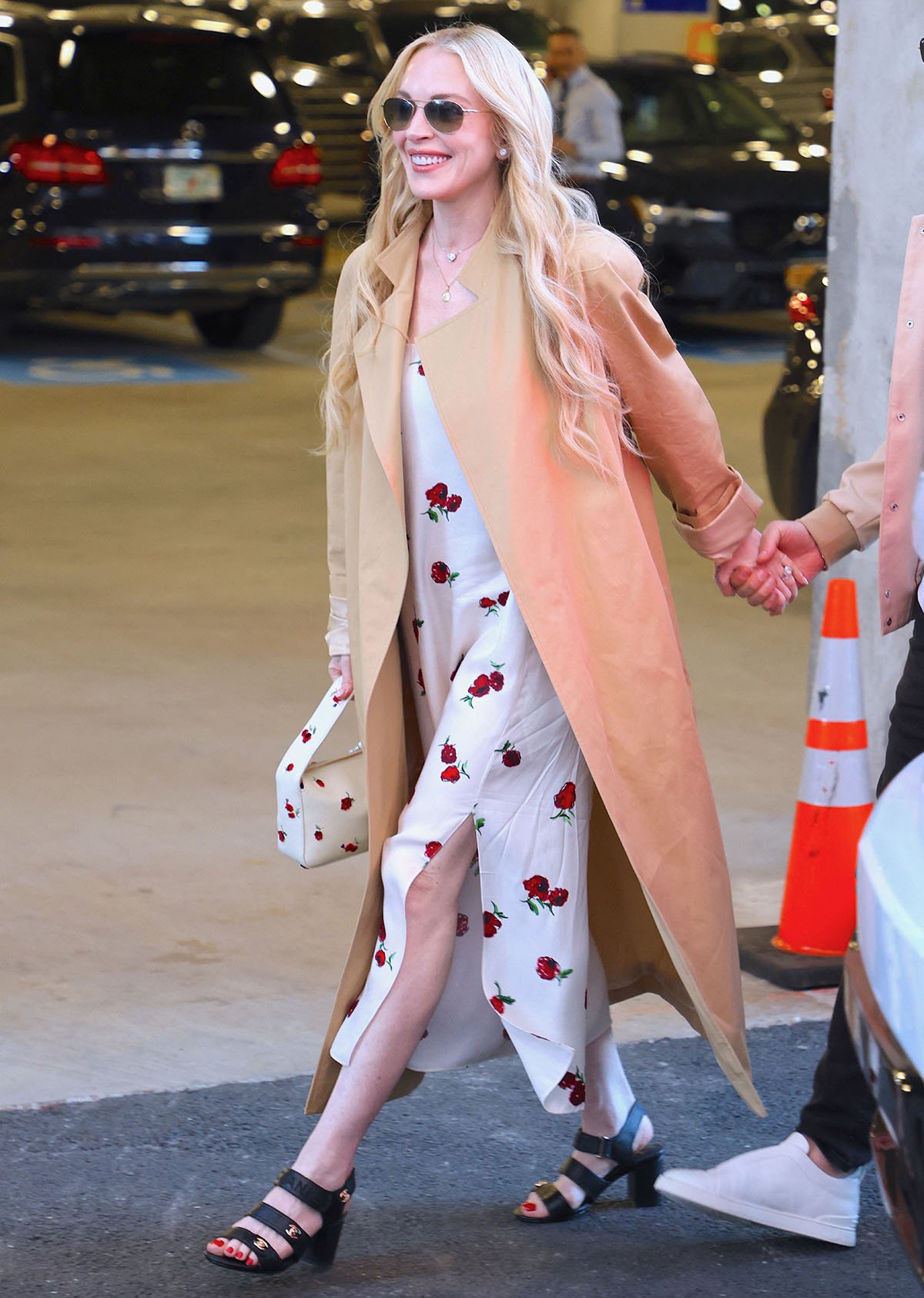 Lindsay Lohan brings feminine charm to the US Open in a white Khaite slip dress with raspberry prints, a square neck with spaghetti straps, and a thigh-high slit