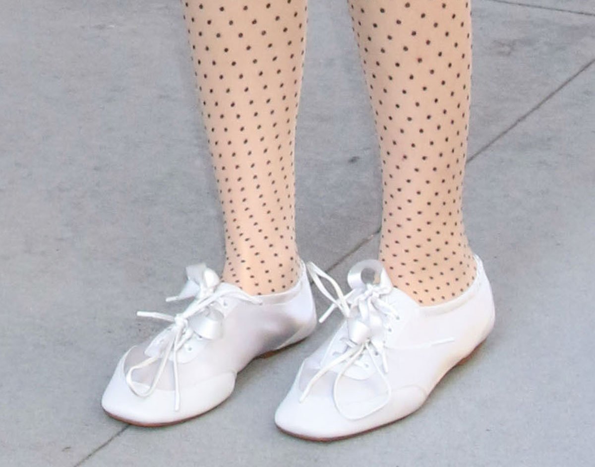 Lola Tung wears this season's shoe trend: ballet sneakers or sneakerina by Vivaia in silky satin with ribbon ties