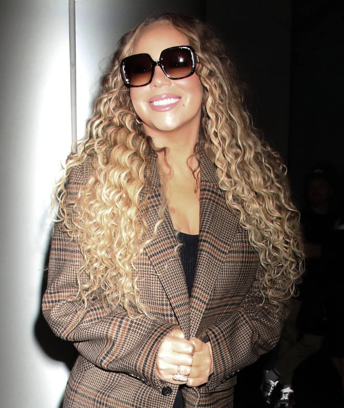 Mariah Carey wears her long blonde hair in voluminous tight curls and shields her eyes behind oversized square-framed sunnies with ombre lenses