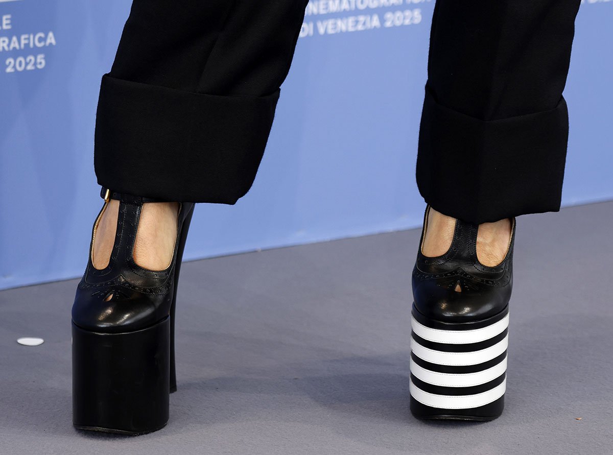 Rebecca Ferguson completes her sleek, tailored look with Thom Browne's brogue-style pumps, featuring a perforated T-strap and round toe, towering block heels, and mismatched plain and striped platforms