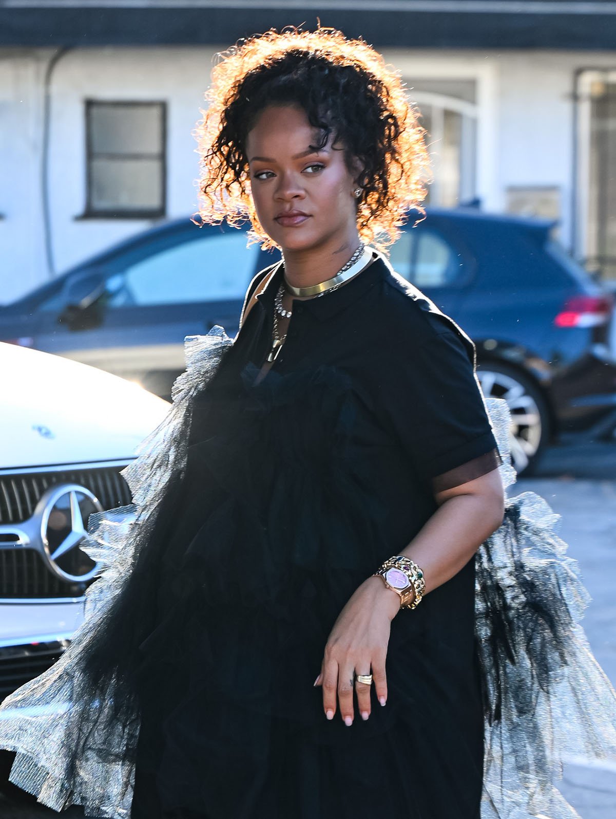 Rihanna styles her ruffled look with an array of necklaces, including one from Marie Lichtenberg, chunky gold chain bracelets, a gold Audemars Piguet Royal Oak watch, and a custom XIV Karats ring