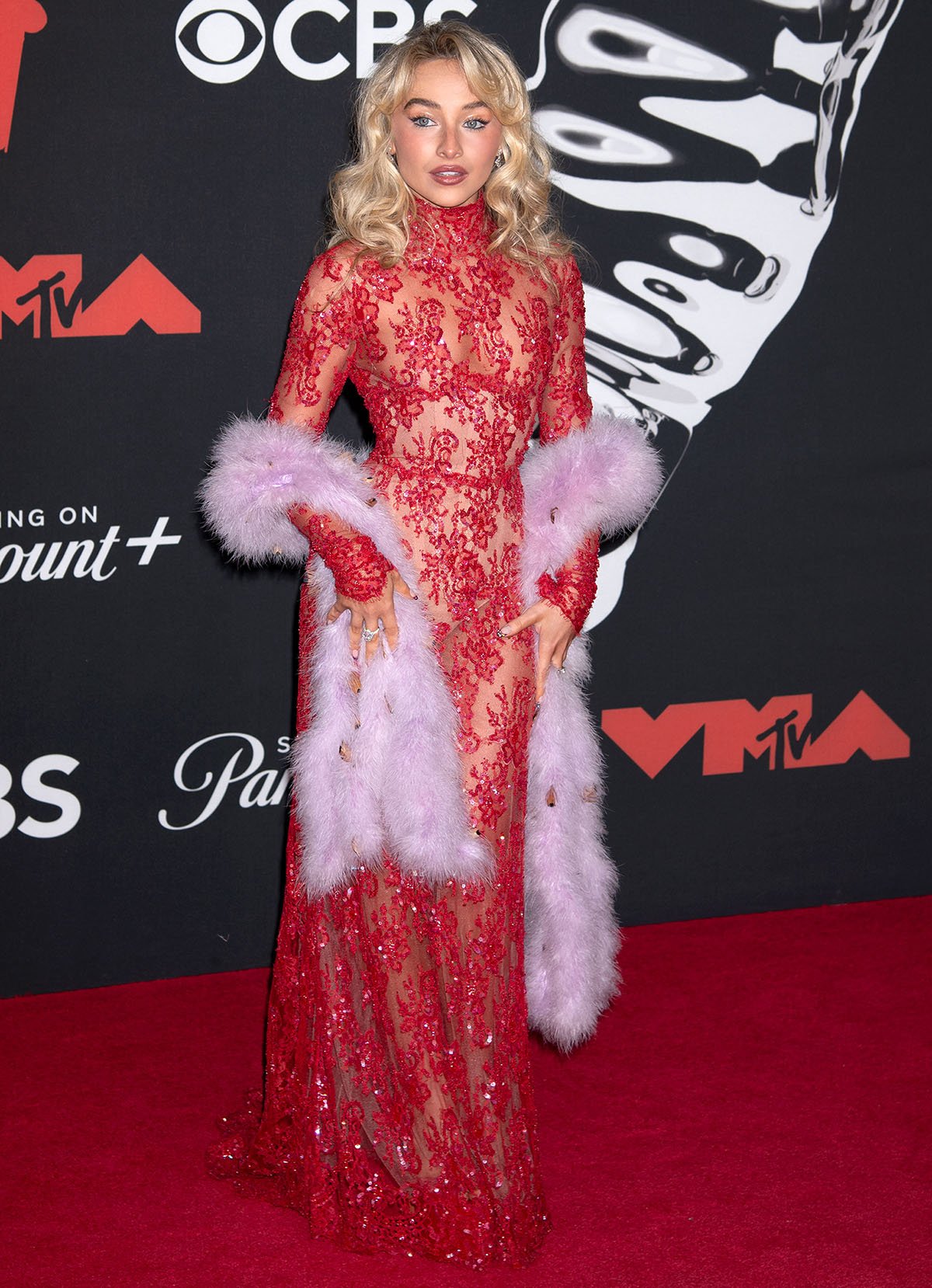 Sabrina Carpenter arrives on the MTV VMAs red carpet wearing a custom red Valentino sheer gown embellished with floral sequins