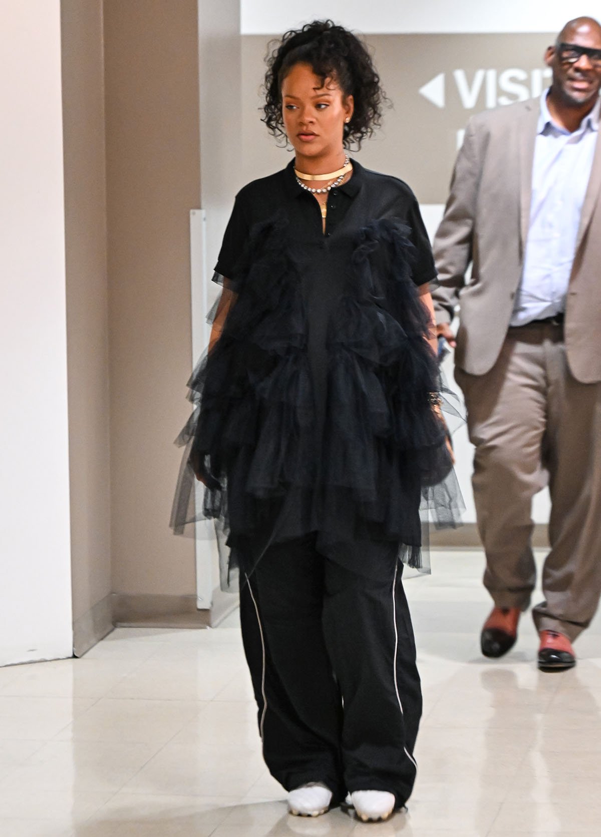 Rihanna embraces balletcore in black Balenciaga track pants and a black Simone Rocha polo shirt featuring tiers of tulle ruffles cascading from the chest to the hem