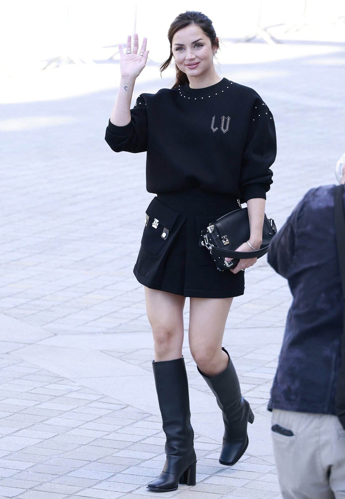Ana de Armas radiates effortless sophistication in a studded Louis Vuitton sweater, mini skirt with utility pockets, and sleek knee-high boots