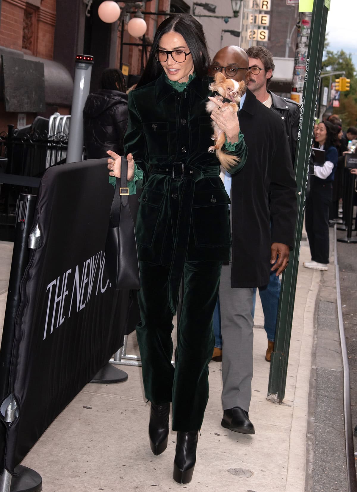 Demi Moore embraces fall glamour in a forest green velvet Saint Laurent suit featuring the Saharienne jacket, straight-leg pants, and a green blouse with ruffled high neck and cuffs