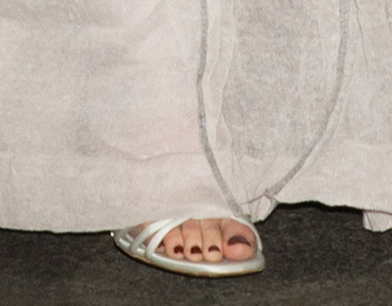 Emma Stone gives a glimpse of her ivory satin open-toe sandals, featuring slim crisscross straps that complemented her sheer Louis Vuitton gown with minimalist elegance
