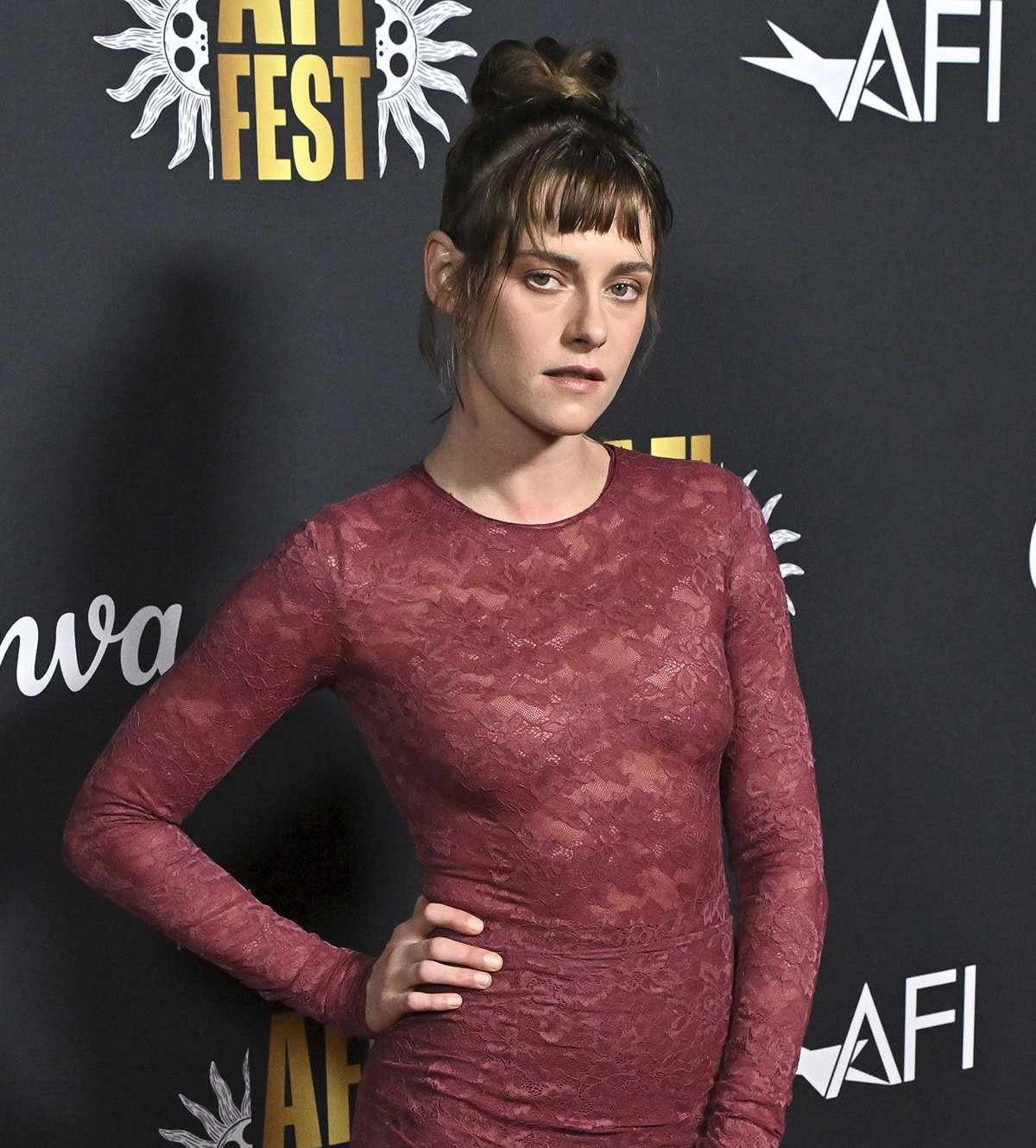 Kristen Stewart styles her hair in a messy but chic high bun with micro bangs and a few wisps framing her face