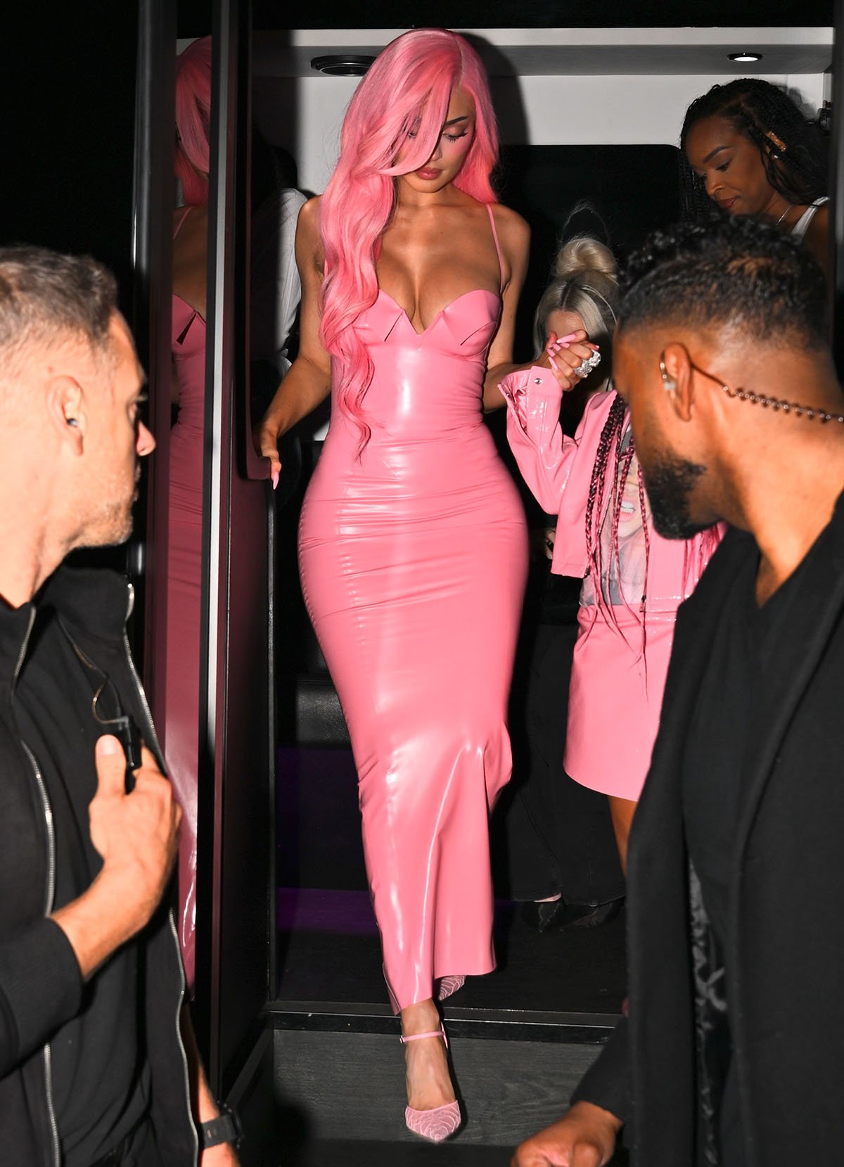 Kylie Jenner showcases her hourglass figure in a pink latex Poster Girl dress featuring a plunging neckline, folded bra cups, and thin shoulder straps