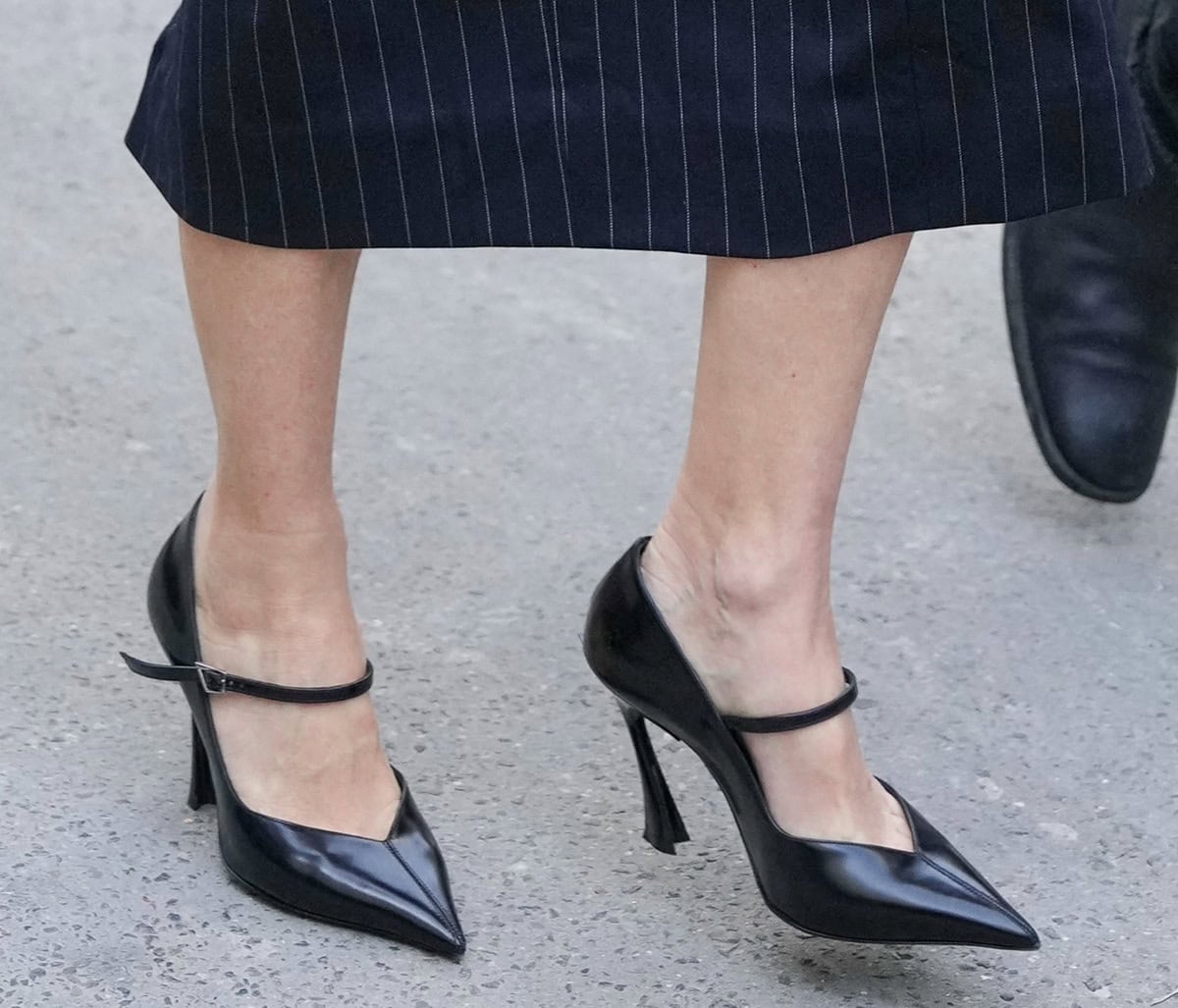 Naomi Watts pairs her sleek business wear with pointy black pumps by Mugler featuring V-shaped vamps, slender Mary Jane straps, and the label's signature fang-shaped heels